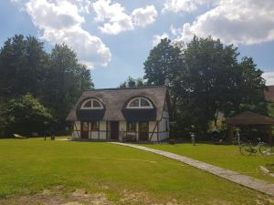 une petite maison sur un champ herbeux avec des arbres dans l'établissement Chata Pod Strzechą, à Lipusz