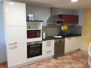 a kitchen with white cabinets and a stove top oven at Les portes du marais in Benet