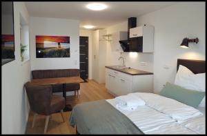 ein Schlafzimmer mit einem Bett und einem Tisch sowie eine Küche in der Unterkunft Fernweg Apartments in Nidderau