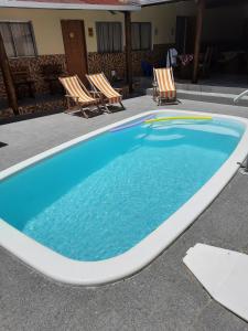 una gran piscina con 2 sillas al lado en Pousada Pelourinho, en Mucuri