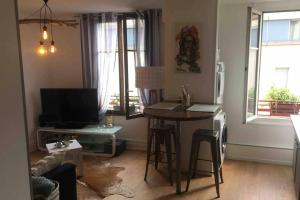 a living room with a table and a television at Le XV in Nancy