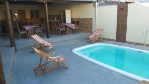 a swimming pool with two chairs and a table and a table and chairs at Pousada Pelourinho in Mucuri