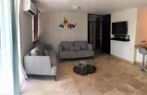 a living room with a couch and a tv at Departamento comodo, a media cuadra de la playa. in Mazatlán