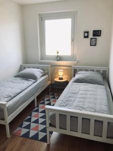 two beds in a bedroom with a window and a rug at Schwarzburg Appartments in Sondershausen