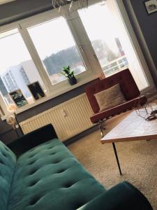 sala de estar con sofá, mesa y ventanas en Schwarzburg Appartments, en Sondershausen