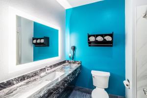a blue bathroom with a sink and a mirror at Americas Best Value Inn & Suites Kingwood IAH Airport in Kingwood +27 photos