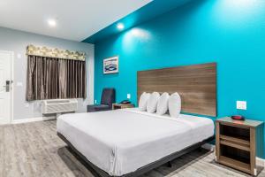 sypialnia z dużym łóżkiem i niebieską ścianą w obiekcie Americas Best Value Inn & Suites Kingwood IAH Airport w mieście Kingwood