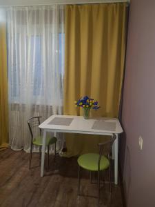 a white table with two chairs and a vase of flowers on it at Apartment Sports Palace Просторная квартира рядом Дворец Спорта in Kharkiv