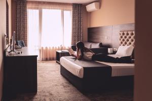 a woman laying on a bed in a hotel room at Plaza Hotel Plovdiv in Plovdiv