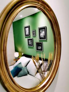 a mirror with a couch in front of a green wall at Premier Chapitre - Design et charme de l'ancien en cœur de ville in Saint-Brieuc