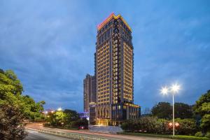 a tall building is lit up at night at Ramada Plaza by Wyndham Wuhan Huangpi in Wuhan