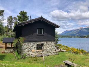 a small stone house on the shore of a lake at Casa de campo con costa de lago in San Carlos de Bariloche