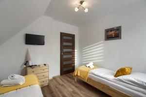 a bedroom with two beds and a tv on the wall at Apartament na Sportowej in Tylicz