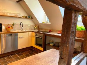 an attic kitchen with yellow cabinets and a sink at Burg Maisonette im Posthalterhof mit Sauna in Blankenheim +11 photos