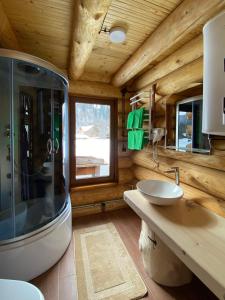a bathroom with a sink and a shower in a log cabin at Chalet PidStromom in Mykulychyn +90 photos