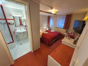 Cette chambre comprend un lit rouge et une salle de bains. dans l'établissement Hotel Zur Goldenen Sonne, à Quedlinbourg