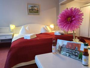 Cette chambre d'hôtel dispose d'un lit rouge et d'une table fleurie. dans l'établissement Hotel Zur Goldenen Sonne, à Quedlinbourg
