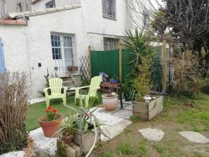 um quintal com duas cadeiras e uma mesa e algumas plantas em Chambre d'Hôte - Mas Le Barret em Arles