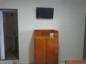 a flat screen tv on a wall with a wooden cabinet at Hotel Karisma II in São Bernardo do Campo