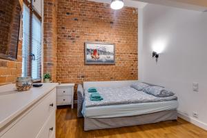 a bedroom with a bed and a brick wall at Apartament Uroczy Zakątek in Gliwice