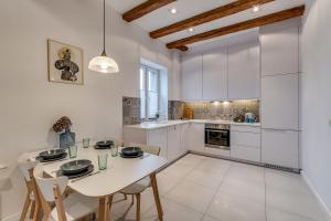 eine Küche mit weißen Schränken sowie einem weißen Tisch und Stühlen in der Unterkunft Apartament Z Widokiem Na Rynek in Gliwice