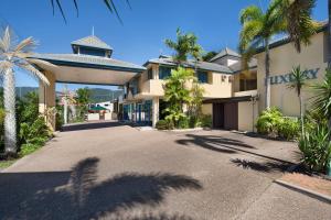 ein Haus mit Palmen vor einer Einfahrt in der Unterkunft Cairns Southside International in Cairns