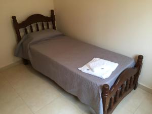 El oasis في Saladillo: سرير صغير في غرفة نوم عليها قميص ابيض