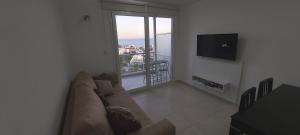 sala de estar con sofá y ventana grande en Torre Orca Piso 9 Mareas del Golfo en Las Grutas