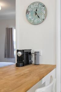 a clock on a wall above a counter with a microwave at Mystics Beach Bungalows in Minnamurra