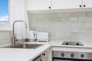 a kitchen with a sink and a counter top at Mystics Beach Bungalows in Minnamurra