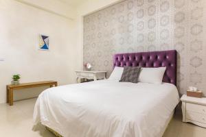 台東市的住宿－大方小正民宿，一间卧室配有一张大床和紫色床头板
