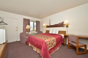 a hotel room with a red bed and a desk and a desk at Americas Best Value Inn North Platte in North Platte