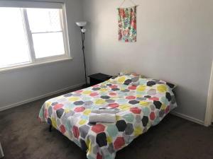 a bedroom with a bed with a colorful comforter at Maddington House Unit C in Perth