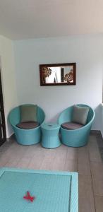a living room with two blue chairs and a mirror at La Digue Self-Catering Apartments in La Digue