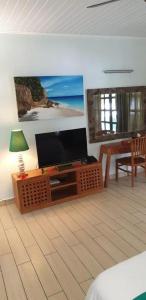 uma sala de estar com uma televisão de ecrã plano e uma mesa em La Digue Self-Catering Apartments em La Digue