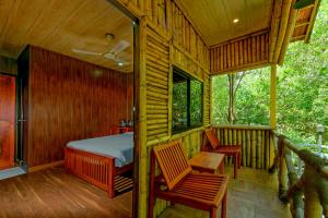 a bedroom with a bed and two chairs on a porch at GoGo Land Resort & Adventurous Sports in Pūvār