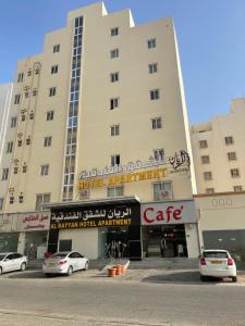 een groot gebouw met auto's geparkeerd voor het bij Al Rayyan Hotel Apartments Muscat in Seeb