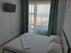 a bedroom with a white bed and a window at Mamaia Dorin Apartment in Mamaia
