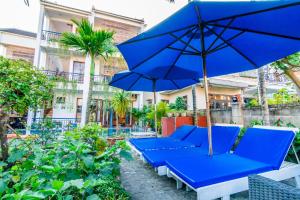 un groupe de bancs bleus avec un parapluie dans l'établissement Relax Garden Boutique Villa Hoi An, à Hội An