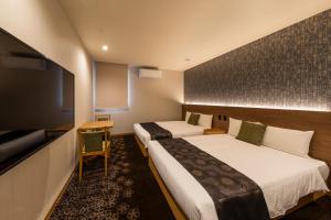 a hotel room with two beds and a flat screen tv at Chiyokura HOTEL SHUKU Nagoya in Nagoya