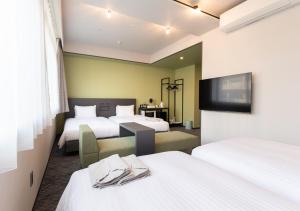a hotel room with two beds and a tv at Hotel Cocktail Stay Naha in Naha