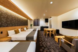 名古屋市にあるグランドベース名古屋-千代倉-のベッド3台とテーブルが備わるホテルルームです。