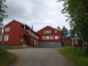 un granero rojo grande con una entrada delante de él en STF Kvikkjokk Fjällstation, en Kvikkjokks Kapell