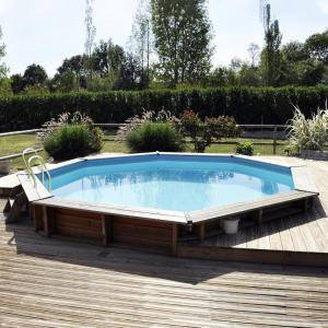 a large pool on a deck with a chair around it at Cottage du garlai in Bressuire