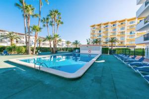 a swimming pool with lounge chairs and a resort at Apartamento Arcoiris, con piscina y junto a playa de Alcudia in Alcudia