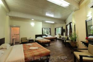 ダージリンにあるDarjeeling Tourist Lodgeのベッド2台、テーブル、椅子が備わる広い客室です。