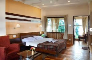 a bedroom with a bed and a couch and a chair at Darjeeling Tourist Lodge in Darjeeling