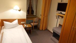 a hotel room with a bed and a desk with a television at Gasthof Russenbräu in Tiefenbach