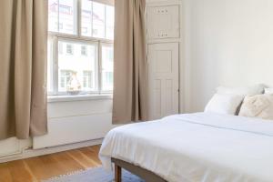 a white bedroom with a bed and a window at Roost Huvilakatu in Helsinki