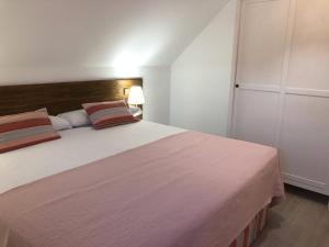 a bedroom with a large bed with a pink blanket at Casa Navalhorno- barrio nuevo Valsain in Segovia